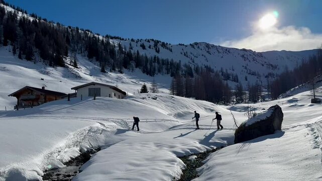 Skitourers crossing snowy valley stream in Kitzb&uuml;hel Alps