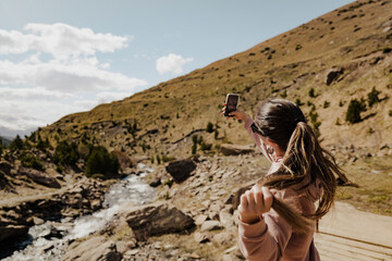 Woman taking selfie in mountain landscape with flowing river