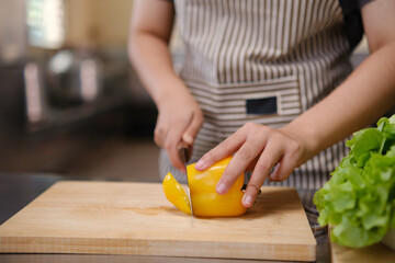 Young woman slicing vegetables in kitchen.