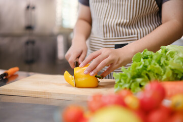 Young woman slicing vegetables in kitchen.