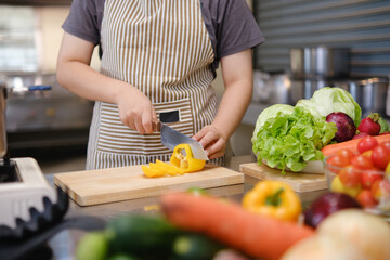 Young woman slicing vegetables in kitchen.