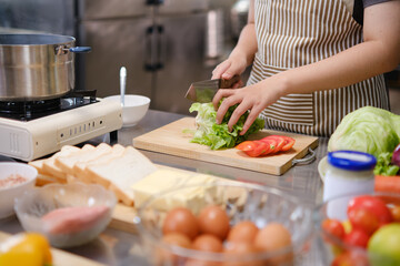 Young woman slicing vegetables in kitchen.