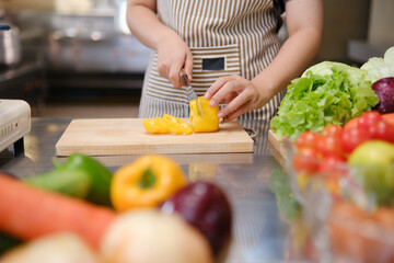 Young woman slicing vegetables in kitchen.