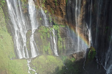 Experience majestic waterfalls with a rainbow at tumpak sewa indonesia - nature aerial photography in lush greenery