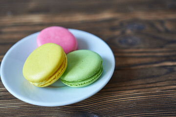Colorful macaroons on a plate on a wooden background.