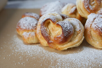 Sweet buns sprinkled with powdered sugar on a wooden table. Selective focus.