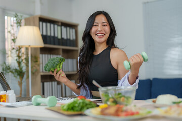 Asian nutritionist holding broccoli and dumbbell promoting healthy eating and active lifestyle,...