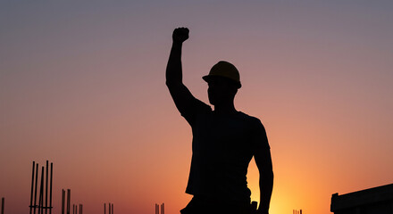 Fototapeta premium Silhouette of Construction Worker Raising Fist at Sunset