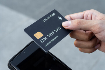Close-up of man's hand holding credit card outdoors, paying bill online via smartphone. finance, investment, online payment, online shopping, savings
