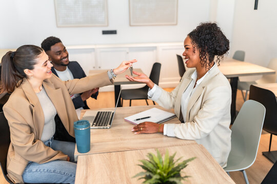 Real estate agent giving keys to happy couple after successful deal