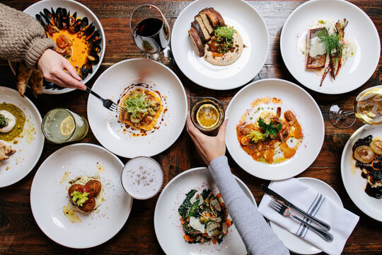 Two female hands reaching over tabletop food spread