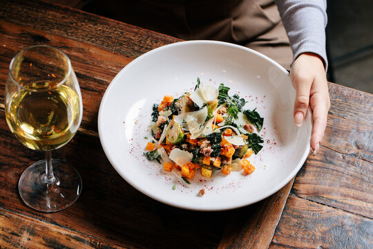 Female hand holding dish with glass of wine