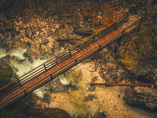 A fast-flowing mountain river winds through a dense forest near Kranjska Gora, Slovenia. Surrounded by evergreen trees and natural rocks, the clear water rushes over the rocky riverbed.