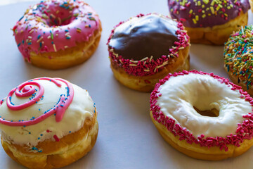 Glazed and decorated donuts in a box, showcasing a variety of flavors and toppings, with vibrant icing colors, set on a wooden table, perfect for a sweet treat or dessert
