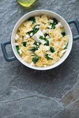 Serving pan with spanakopita pasta on a dark-grey granite background, vertical shot with copy space, above view