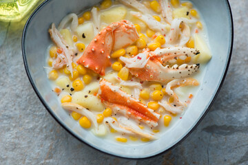 Blue bowl with crab and corn chowder, horizontal shot, middle closeup, selective focus