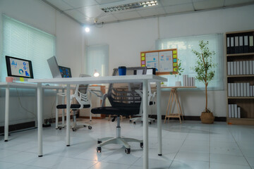 Empty modern office interior featuring graphs and charts on computer screens, colorful sticky notes on a board, and a small potted tree, emphasizing data analysis and a pleasant work environment