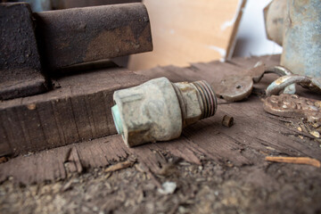 Macro view of a bolt, washer, and nut resting on a dusty wooden surface. Ideal representation of rustic hardware details often found in rural or farm-based mechanical environments.