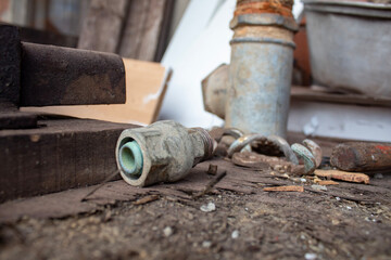 Close-up of an old valve mechanism on a dirty wooden surface, surrounded by dust and debris. This image highlights rustic, perhaps forgotten, utility infrastructure in a rural environment.