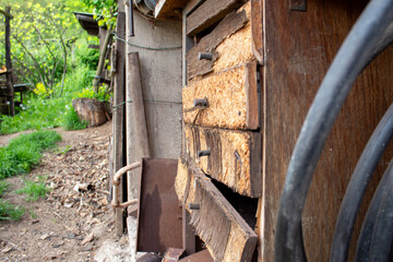 Close-up of the side of a wooden shed with thick black cables hanging along the wall. The rough wood texture and tools suggest rural functionality and a hands-on approach to repairs.
