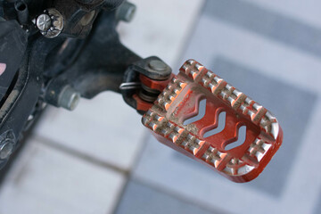 Close up of a motorcycle footrest or footpeg, showing a metal surface with grip texture used for rider foot support and stability