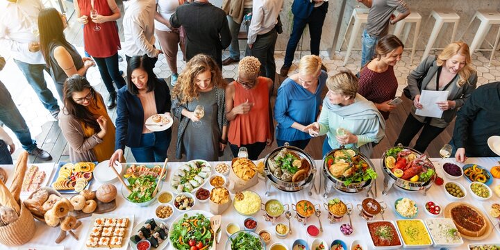 Diverse group enjoying a buffet with various dishes. People of different ethnicities gather around a table, food and conversation at a social event. Business people at international lunch buffet.