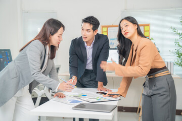 Asian businesspeople having a meeting in a modern office, analyzing financial data and planning new strategy, working together in a modern office with graphs and charts on the table