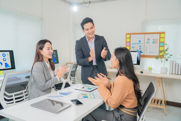 Asian businesspeople celebrating success by clapping hands after an impactful marketing presentation during a dynamic meeting in a modern office environment