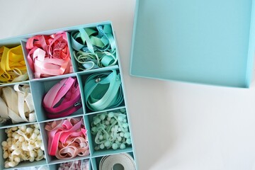 Colorful ribbons, cords and zippers in blue box on white background