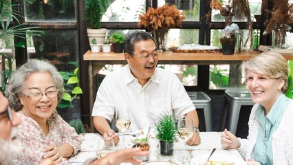 Group of older adults enjoying a meal together. Smiling seniors, diverse ethnicities, sharing laughter. Happy gathering, joyful seniors. Senior diverse people eating lunch at a restaurant.