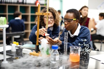 Students in science lab conduct experiment. Diverse students study science in school lab. Students focus on science experiment at school. Diverse students in science class conduct experiment