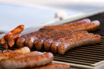 Close-up of frying sausages heated on grill at town square named Bellevue at Swiss City of Zürich on a spring day. Photo taken April 28th, 2025, Zurich, Switzerland.