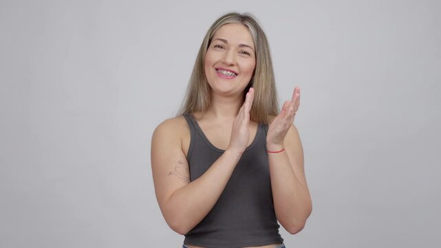 Portrait shot of a casual young woman clapping for team on white background.
