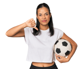 Young Filipino woman with soccer ball showing a dislike gesture, thumbs down. Disagreement concept.