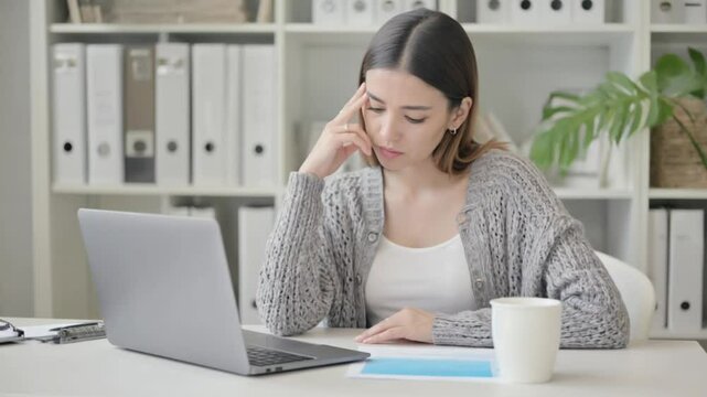Serious young businesswoman working on a laptop in the office