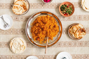 Middle Eastern meal with rice, flatbreads, and salad. Rice and flatbreads are central, surrounded by vibrant salad. Traditional Middle Eastern dining setup. Indian food, top view image.