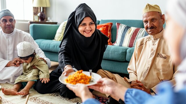 A muslim family enjoying a meal together. Middle Eastern family, traditional attire, sharing food. Smiling, togetherness, cultural celebration, family gathering. Muslim family having a feast.