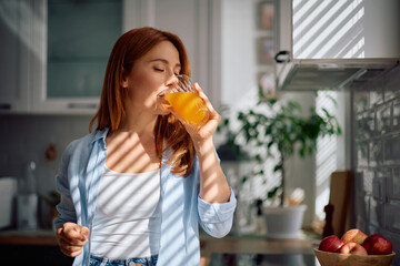 Mid adult woman drinking orange juice in morning.