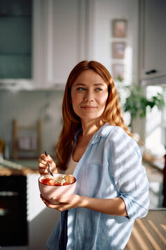 Smiling woman enjoying in healthy food for breakfast in kitchen.