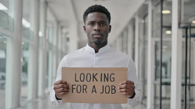 A Serious Black Man holding a card, text LOOKING FOR A JOB