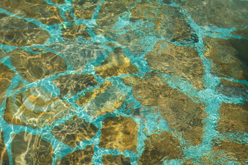 transparant crystal clear water over blue marble or stone tile texture on swimming pool floor with ripples