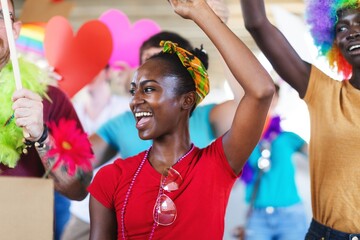 Joyful celebration with diverse group. Smiling woman in red shirt, colorful headband, and beads....