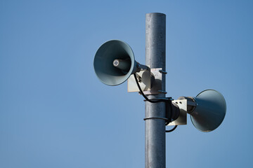 two loudspeakers on a pole against a blue sky background