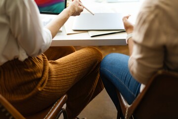 Women working together in a startup business, planning marketing strategies. Startup business collaboration in marketing meeting with two women working in an office. Team meeting in office.