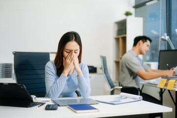 Asian woman feeling migraine head strain.Overworked businesswoman financier while working