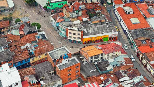 Aerial orbit of people walking on cobblestone streets in the tile-roofed neighborhood of La Candelaria in Bogota, Colombia.