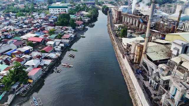 Close aerial shot highlights factory chimneys pumping smoke beside tightly packed shanty homes on the Cagayan de Oro coast, exposing environmental and social issues.