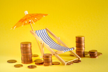 rising prices for vacation and summer holidays or wealth management concept,heap of coins, sun umbrella and deck chair, free copy space. Close up shot with narrow depth of field.