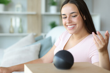 Happy woman is talking to smart speaker at home