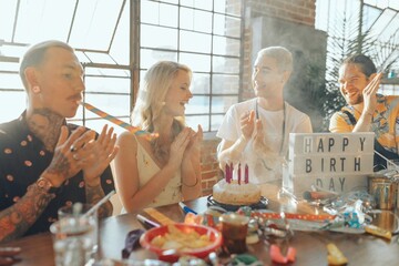 Group celebrating birthday with cake and candles. Diverse friends, festive atmosphere, joyful party. Happy birthday celebration with friends and cake. Diverse friends celebrate festive birthday party.
